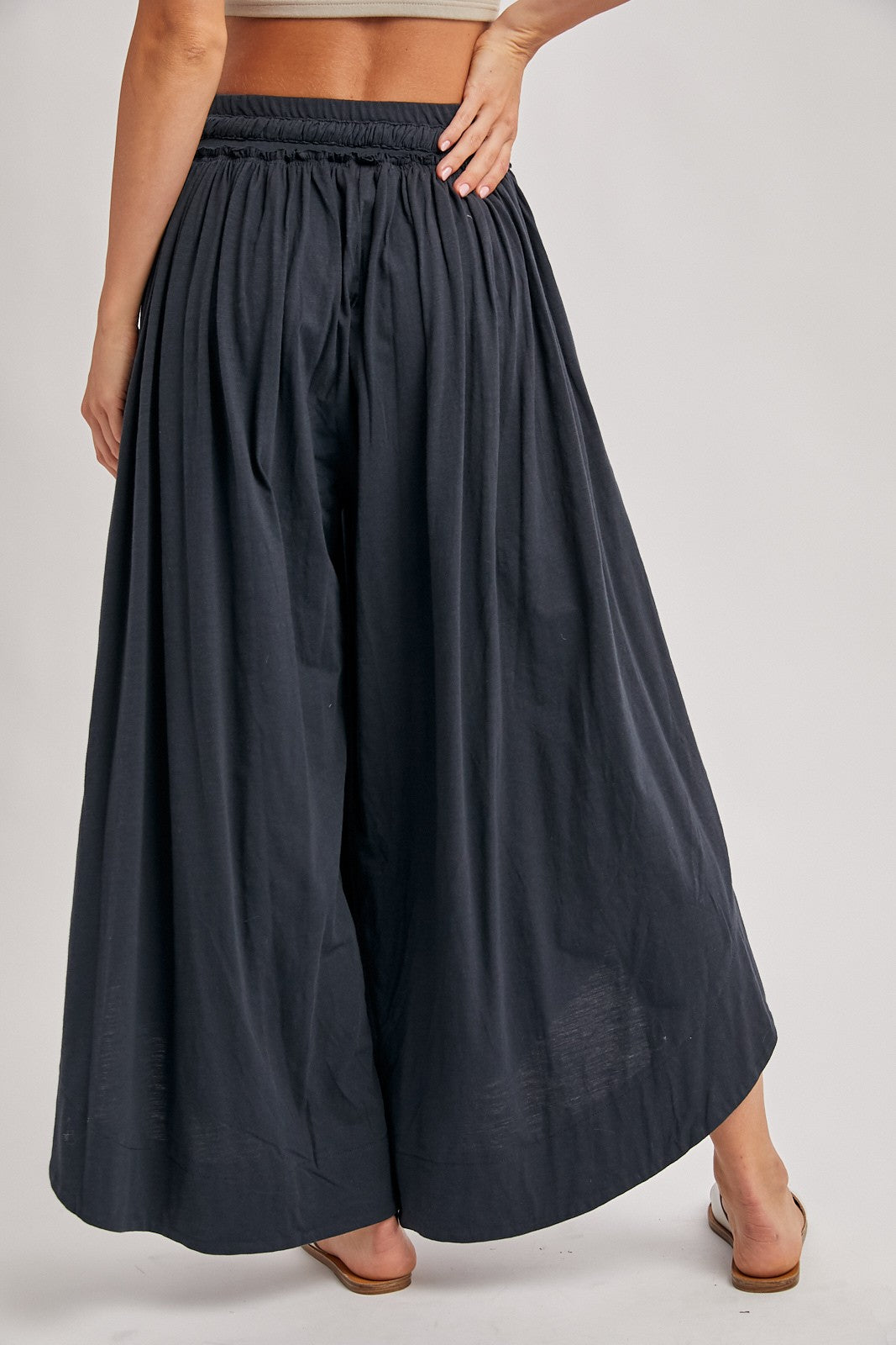 woman wearing black wide-leg palazzo pants with an elastic waistband, shown from the back