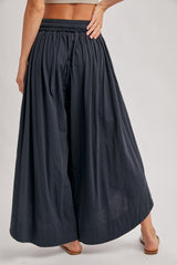 woman wearing black wide-leg palazzo pants with an elastic waistband, shown from the back