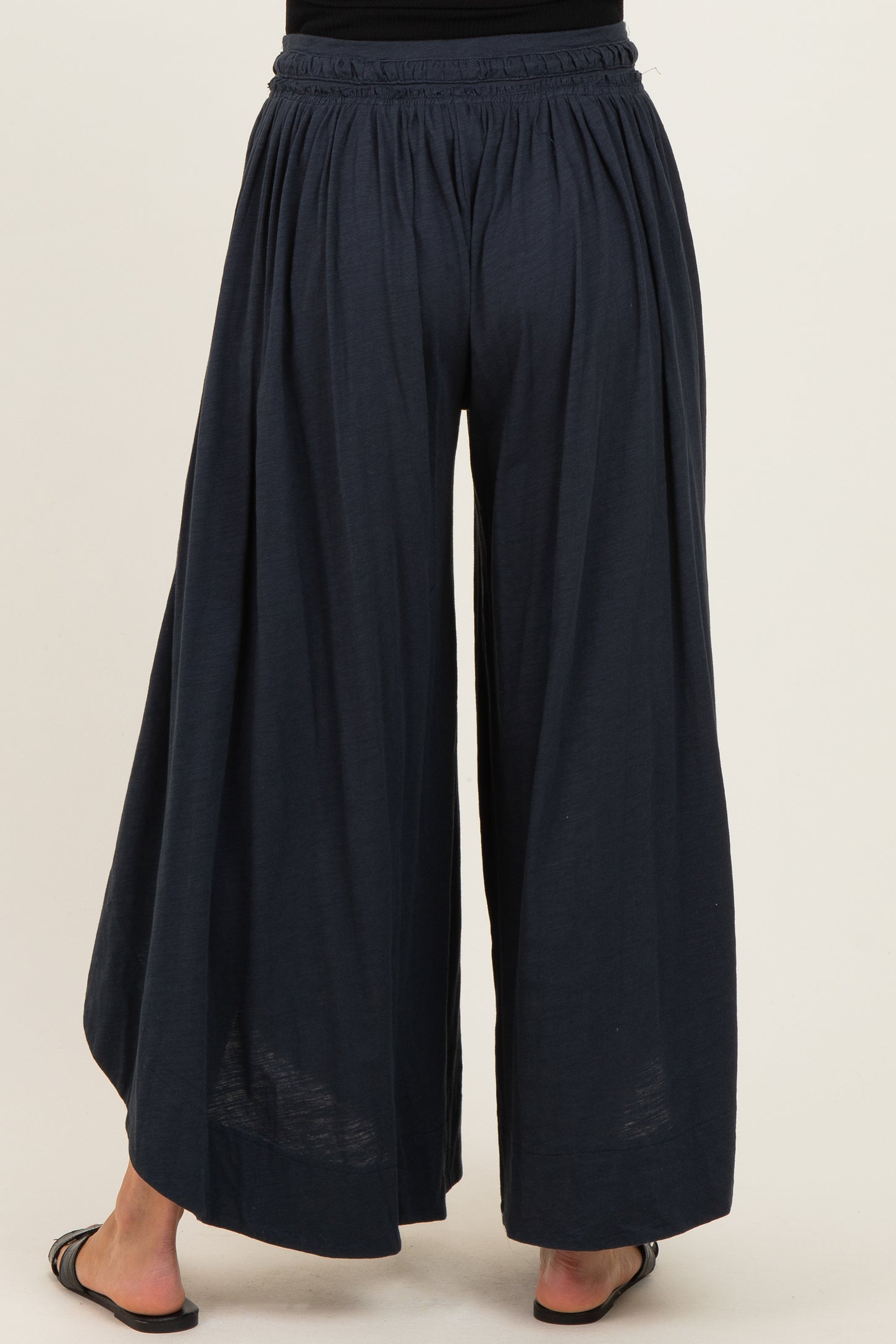 woman wearing navy blue wide-leg maternity pants with an elastic waistband and flowing fabric from the back