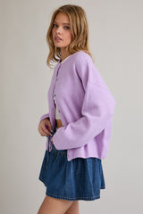woman wearing a light purple oversized cardigan with buttons and a white crop top, paired with a denim mini skirt