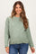 woman wearing a light green maternity cardigan with buttons, paired with blue jeans and showing a baby bump
