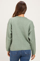 woman wearing a soft green maternity sweater with a relaxed fit, view from the back