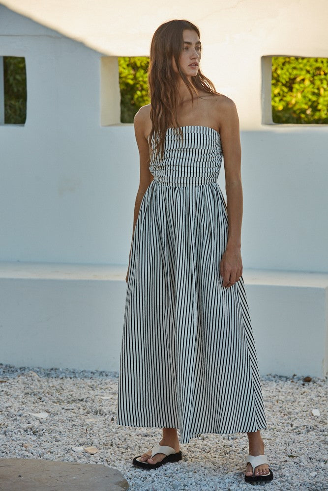 woman wearing a strapless black and white striped maxi dress with a gathered bodice and a flowing skirt