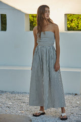 woman wearing a strapless black and white striped maxi dress with a gathered bodice and a flowing skirt