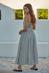 woman wearing a black and white striped strapless maxi dress with a smocked bodice and a flowing skirt