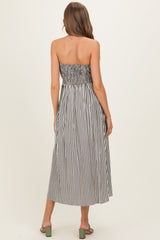 woman wearing a black and white striped maternity maxi dress with a smocked bodice and a flowy skirt
