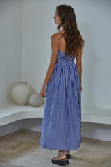 woman wearing a blue and white striped maxi dress with a smocked back, styled with long wavy hair