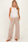 woman wearing a white sleeveless maternity top and beige wide-leg maternity pants with pockets