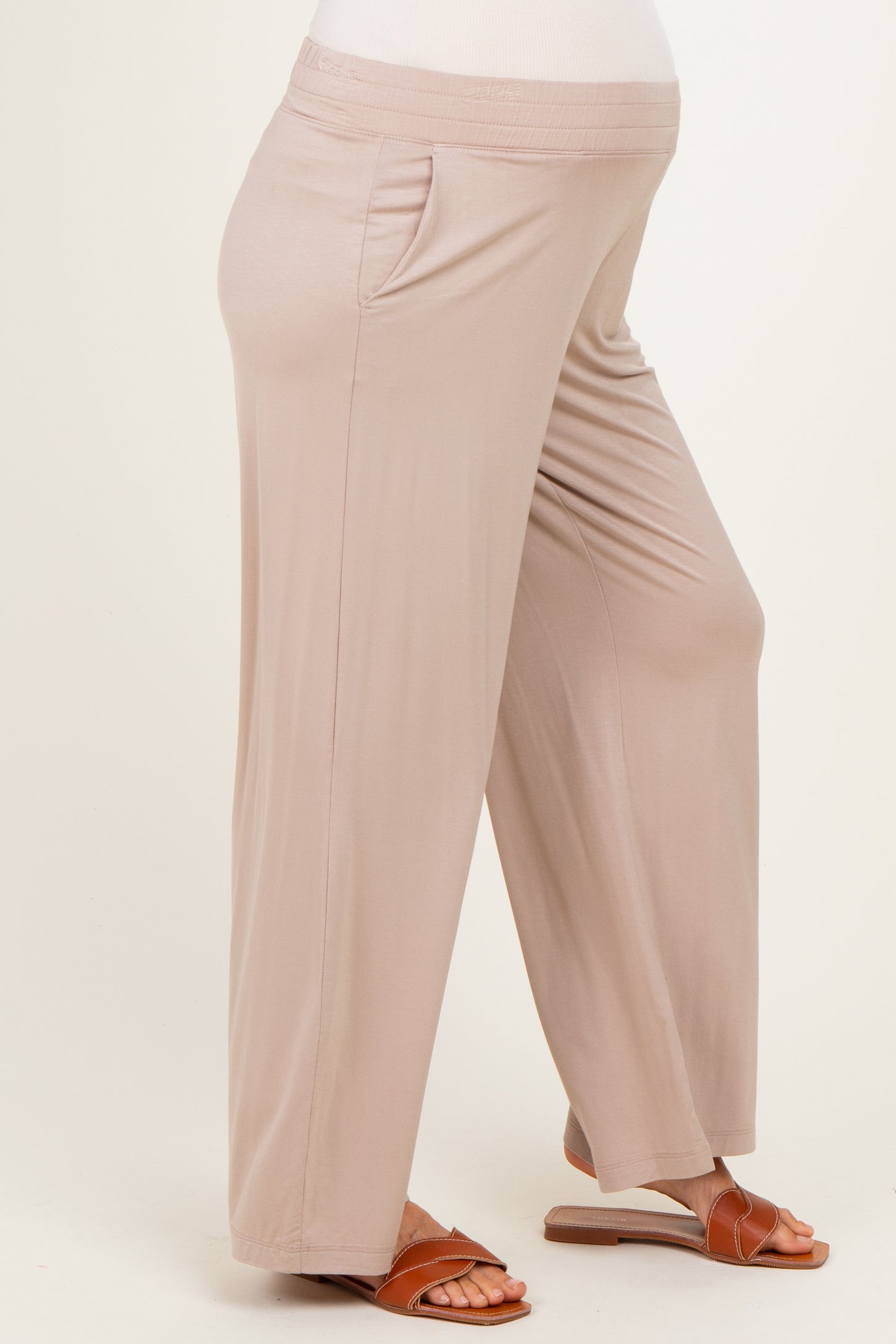 woman wearing light beige maternity pants with side pockets and a visible baby bump
