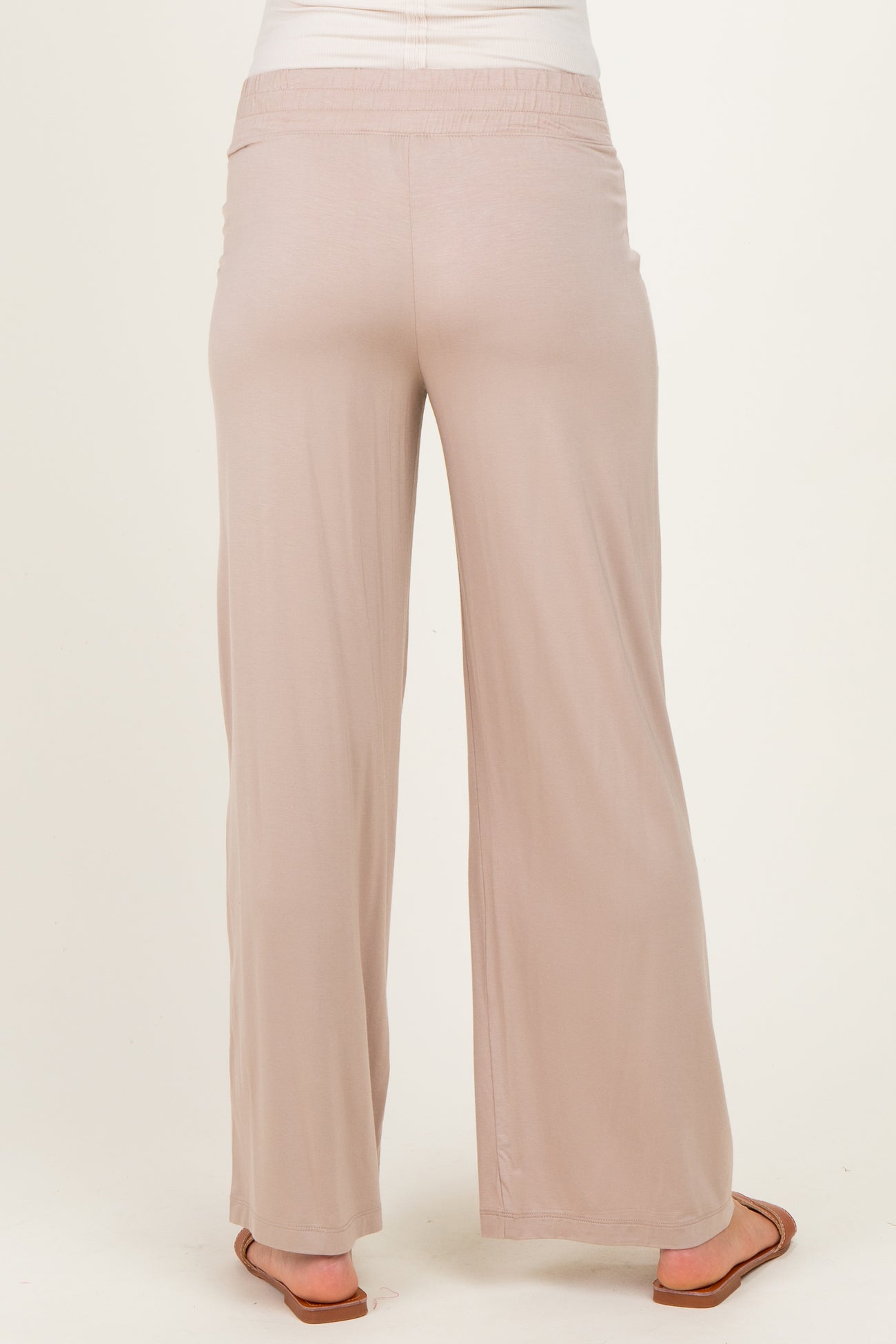 woman wearing light beige maternity pants with a relaxed fit and wide legs, showing the back view