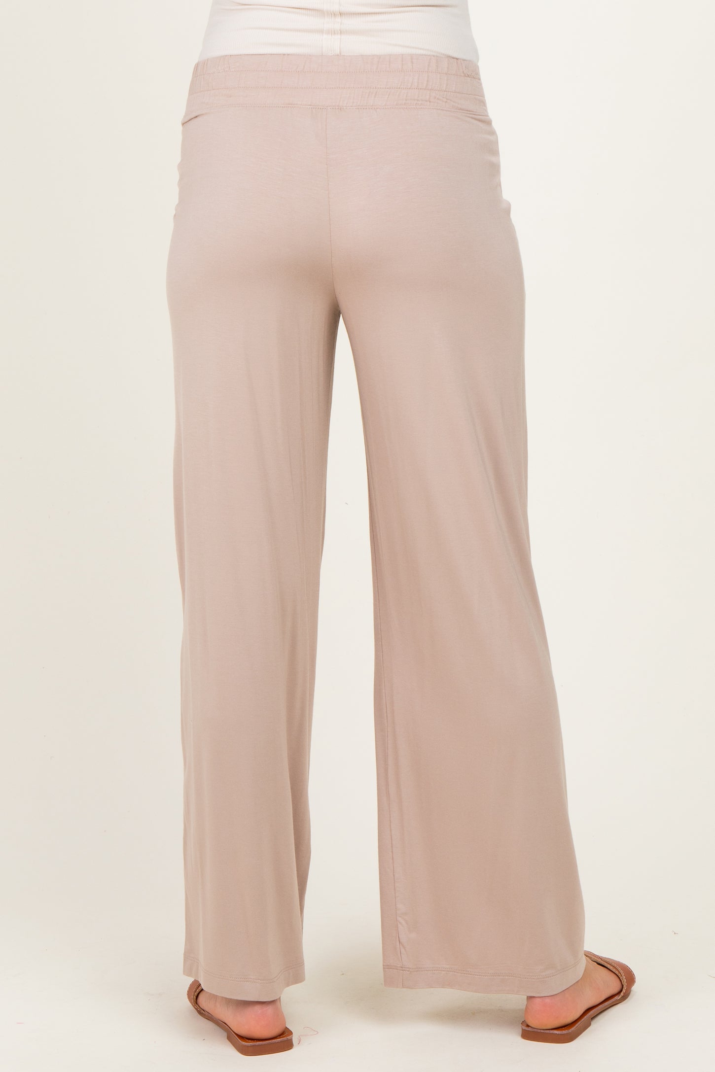 woman wearing light beige maternity pants with a relaxed fit and wide legs, showing the back view