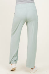 woman wearing light green maternity pants with a comfortable waistband and relaxed fit from the back