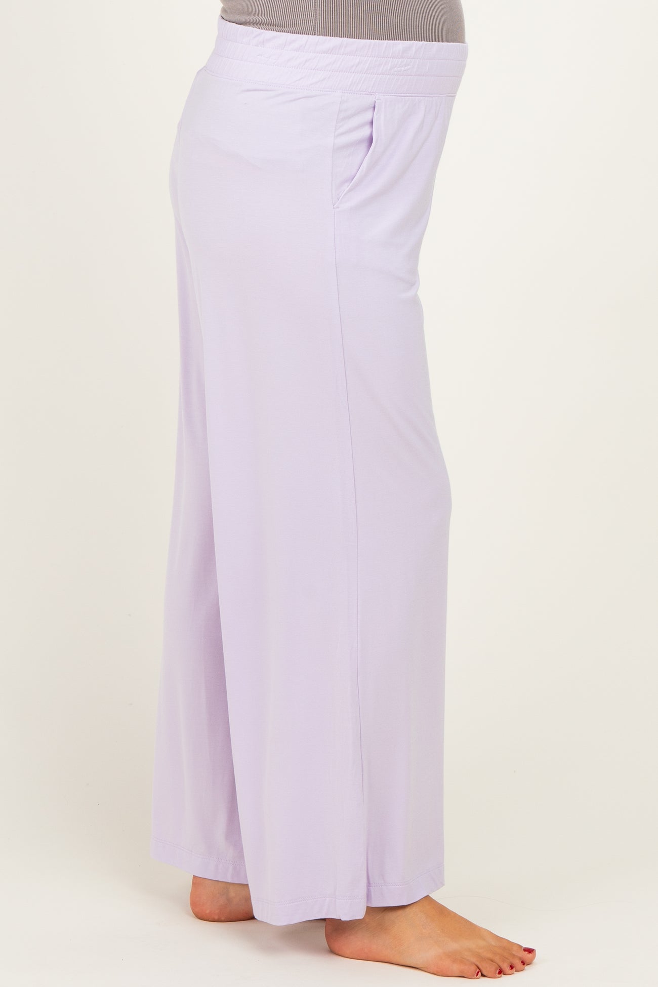woman wearing light purple maternity pants with side pockets and a comfortable elastic waistband, showing her baby bump