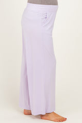 woman wearing light purple maternity pants with side pockets and a comfortable elastic waistband, showing her baby bump