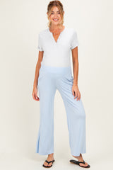 woman wearing a gray henley maternity top and light blue maternity pants with side slits, standing and smiling