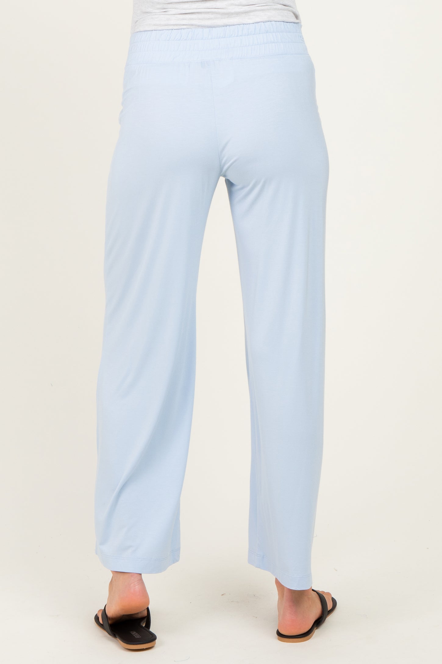 woman wearing light blue maternity wide-leg pants, seen from the back, with an elastic waistband and casual fit