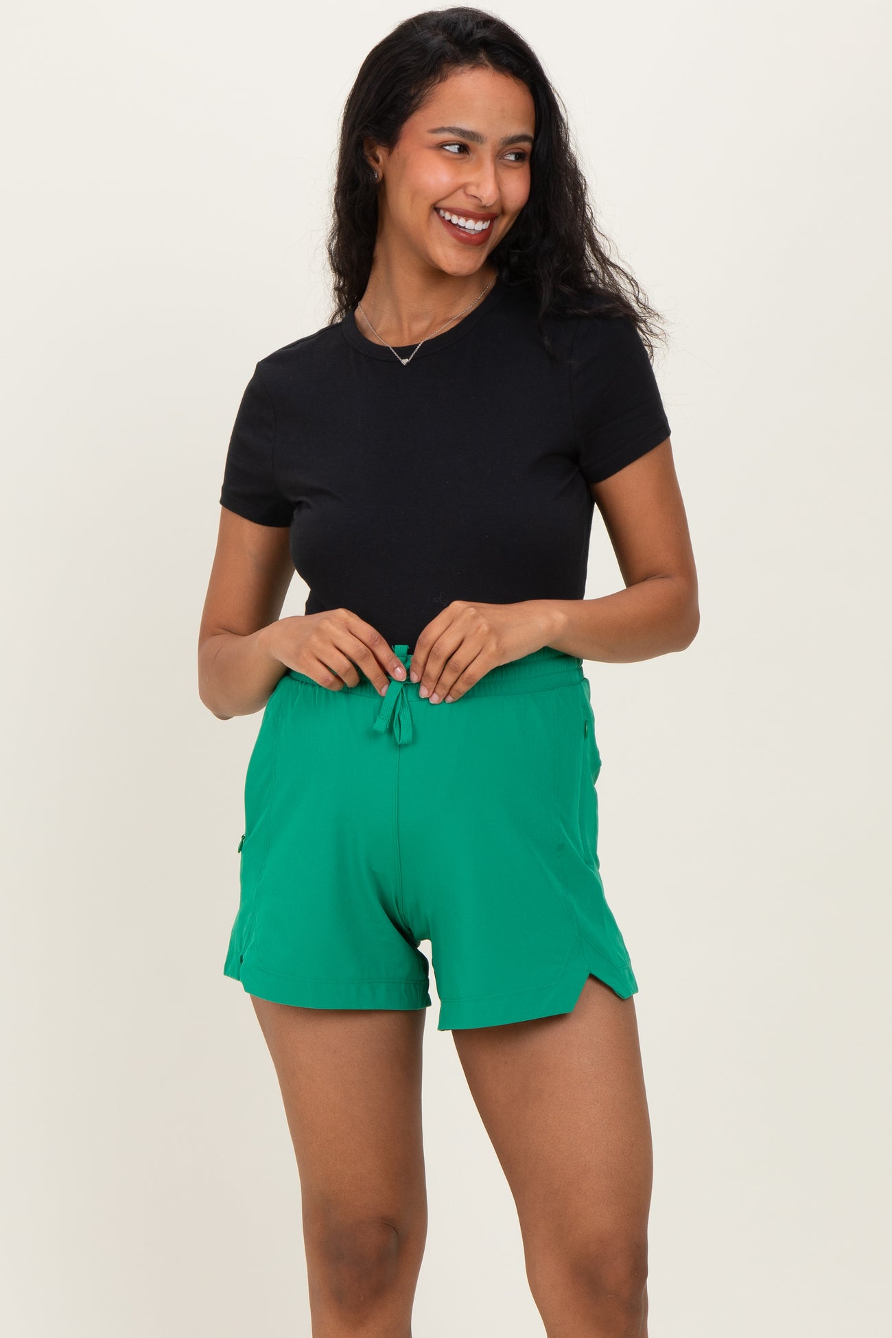 woman wearing a black short sleeve top and green maternity shorts with a drawstring waist