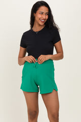 woman wearing a black short sleeve top and green maternity shorts with a drawstring waist