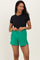 woman wearing a black short sleeve top and green maternity shorts with a drawstring waist