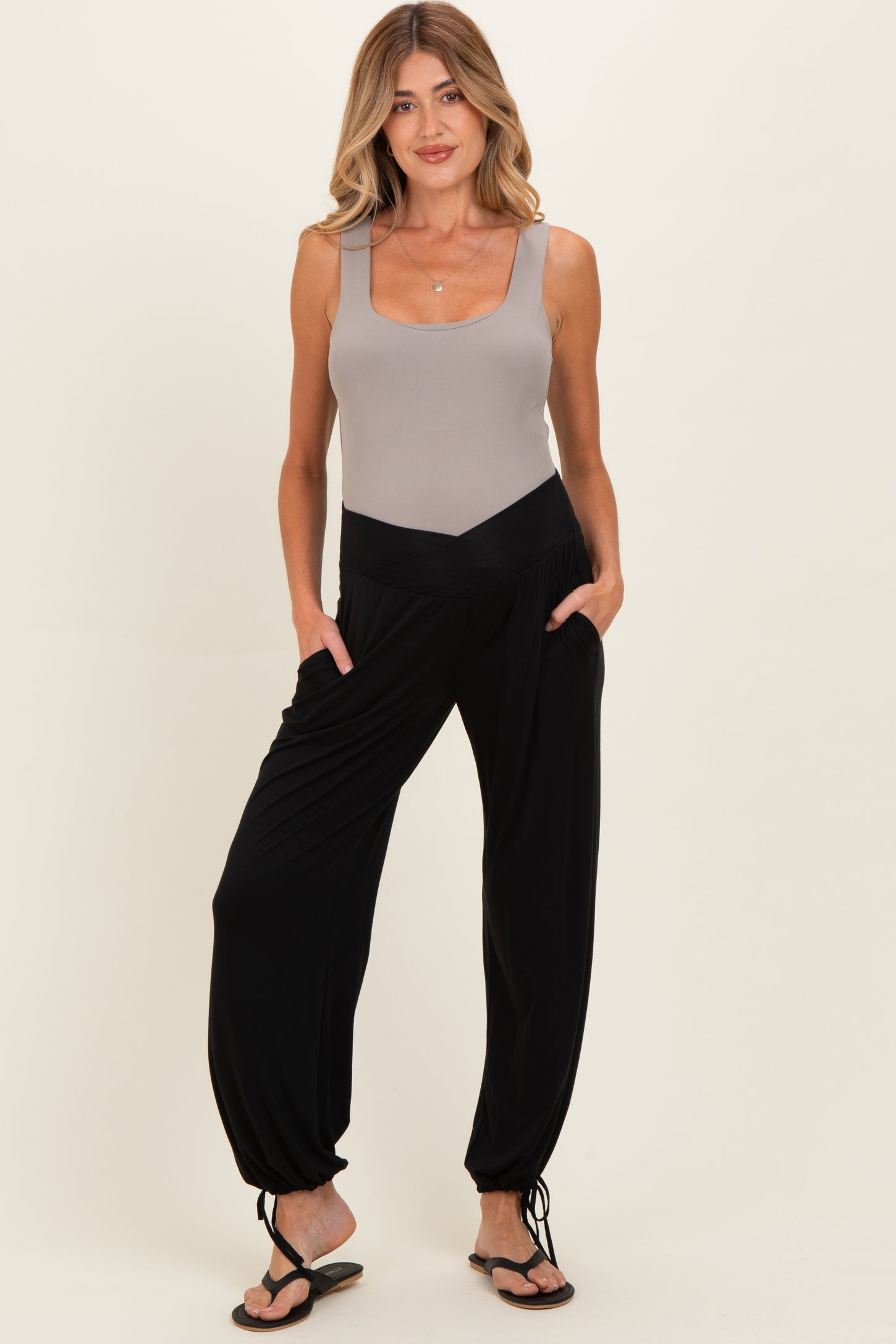woman wearing a grey maternity bodysuit and black harem pants with pockets, styled for comfort