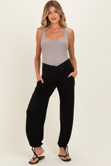 woman wearing a grey maternity bodysuit and black harem pants with pockets, styled for comfort