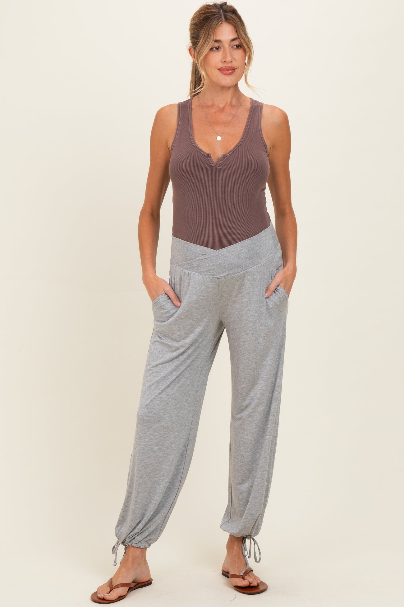 woman wearing a brown ribbed maternity tank top and gray maternity pants with pockets and drawstring cuffs