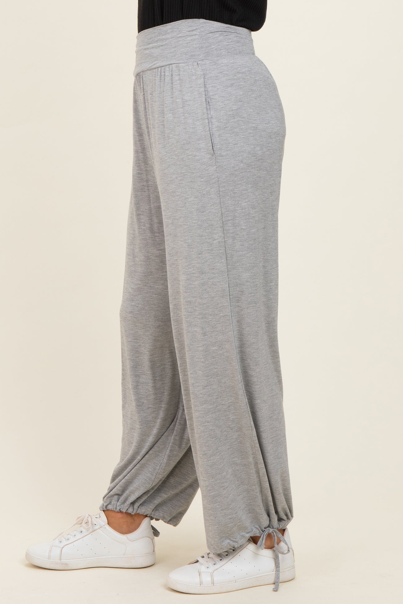 woman wearing light grey wide-leg lounge pants with drawstring cuffs and a relaxed fit, paired with white sneakers