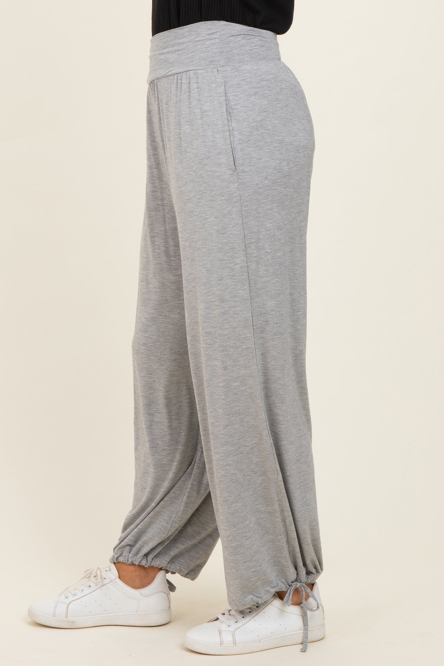woman wearing light grey wide-leg lounge pants with drawstring cuffs and a relaxed fit, paired with white sneakers