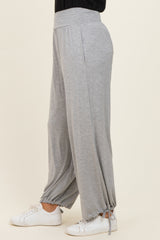 woman wearing light grey wide-leg lounge pants with drawstring cuffs and a relaxed fit, paired with white sneakers