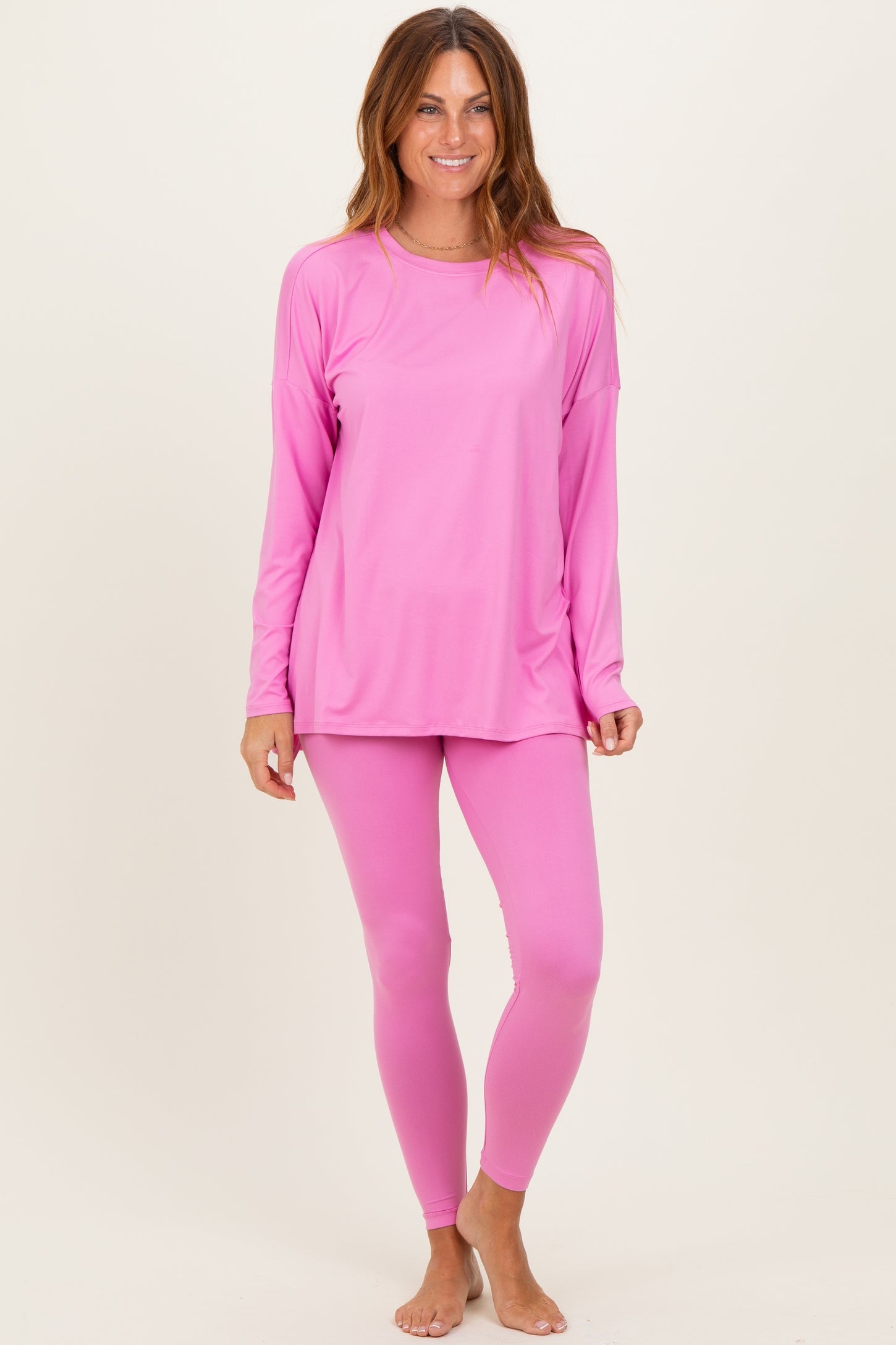 woman wearing a bright pink long sleeve athletic top and matching leggings