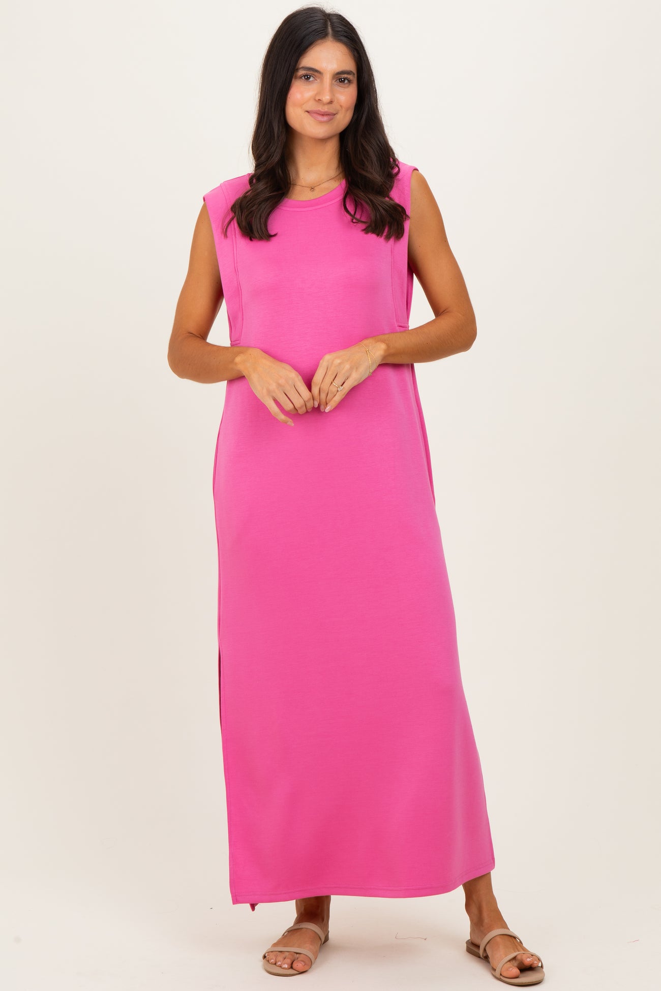 woman wearing a bright pink sleeveless maxi dress with side slits and a relaxed fit