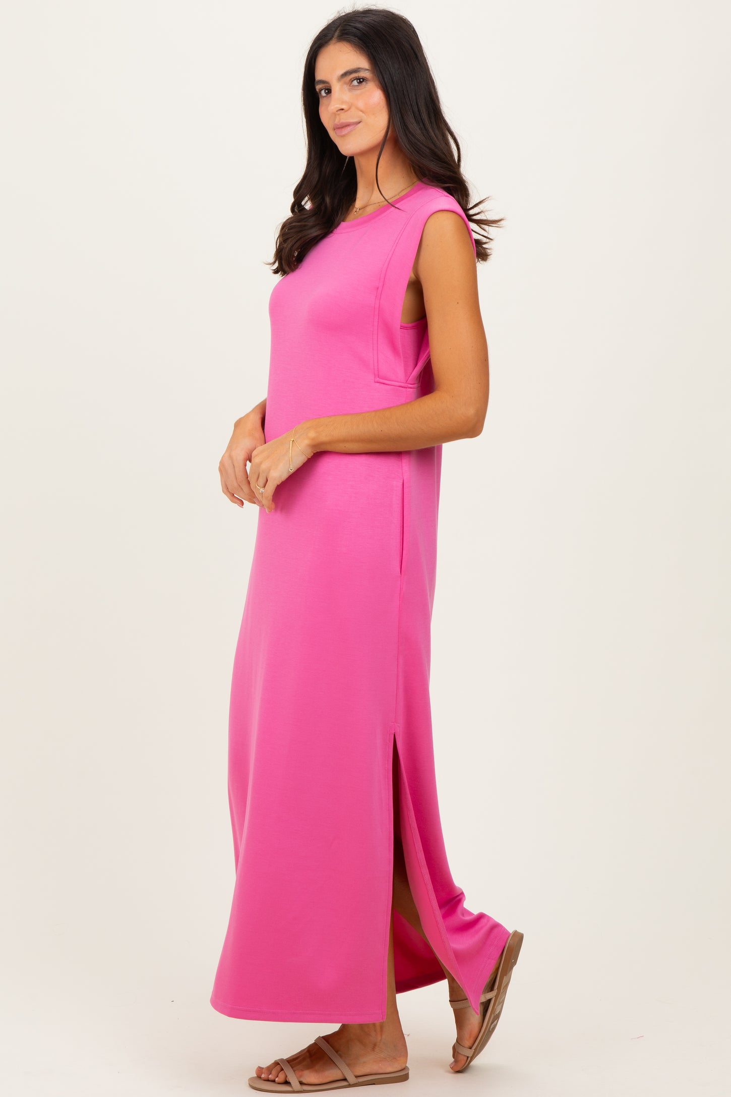 woman wearing a bright pink sleeveless maxi dress with side slits and a relaxed fit