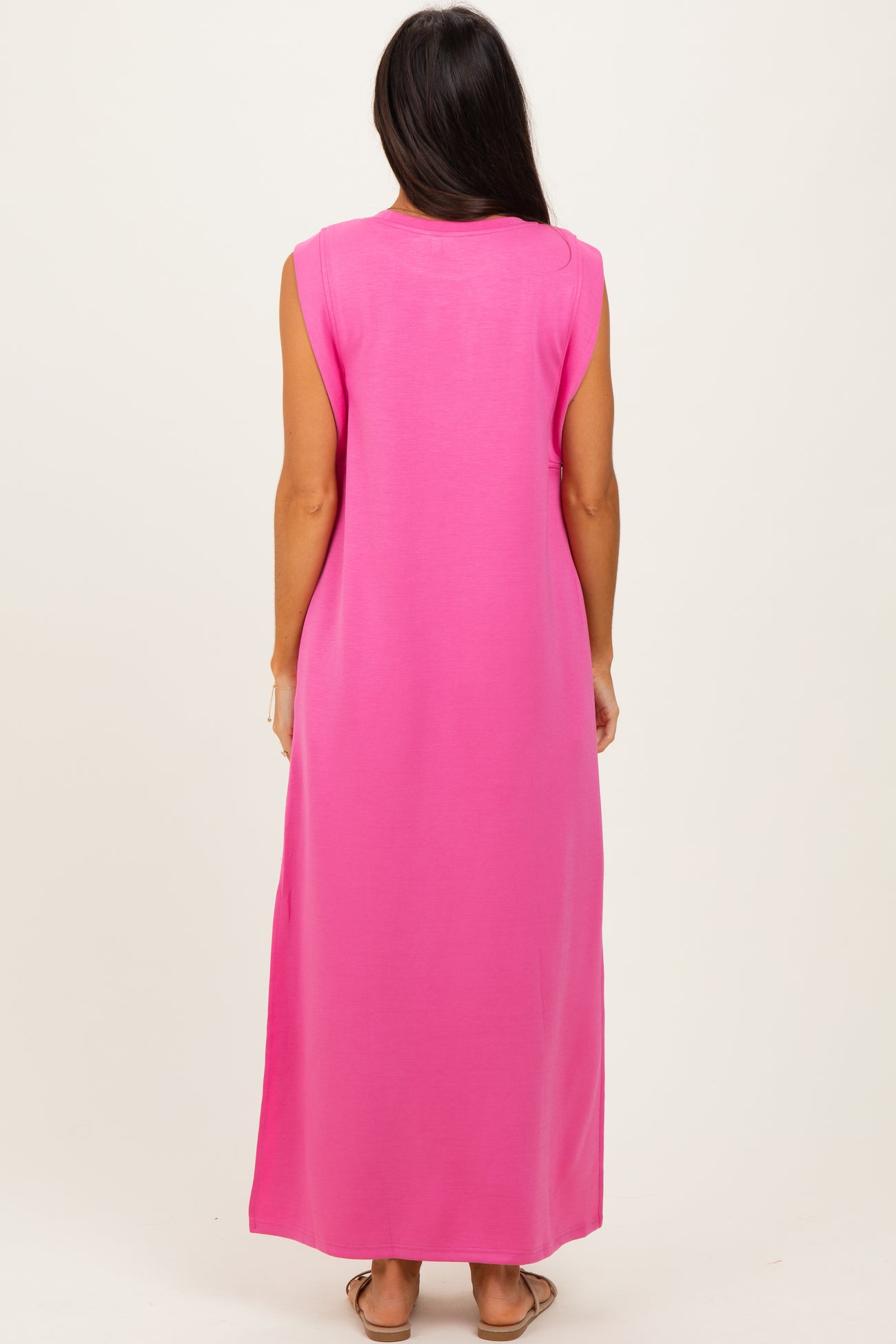 woman wearing a bright pink sleeveless maxi dress, view from the back