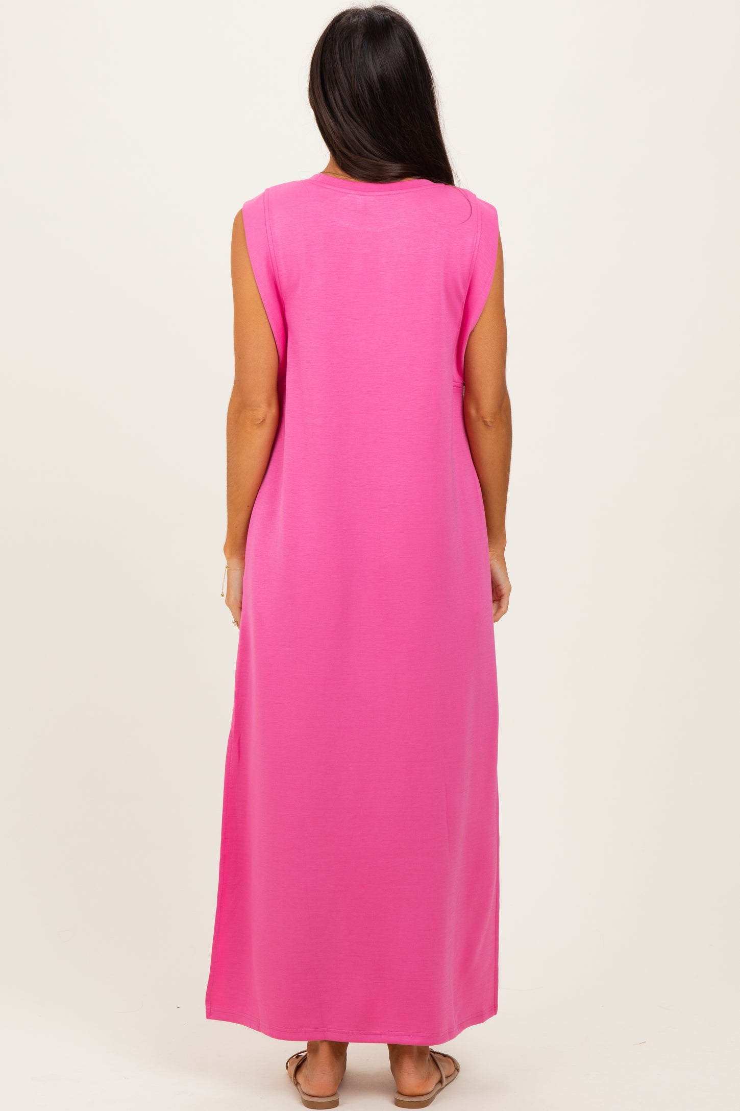 woman wearing a bright pink sleeveless maxi dress, view from the back