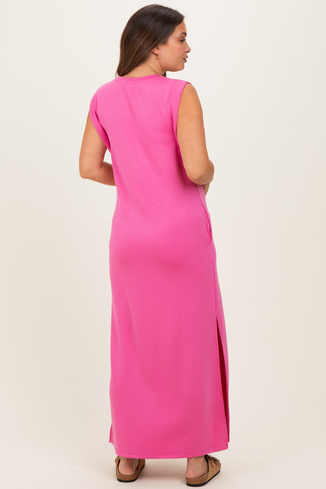 woman wearing a bright pink maternity maxi dress with side slits and a relaxed fit, showing her baby bump from the side