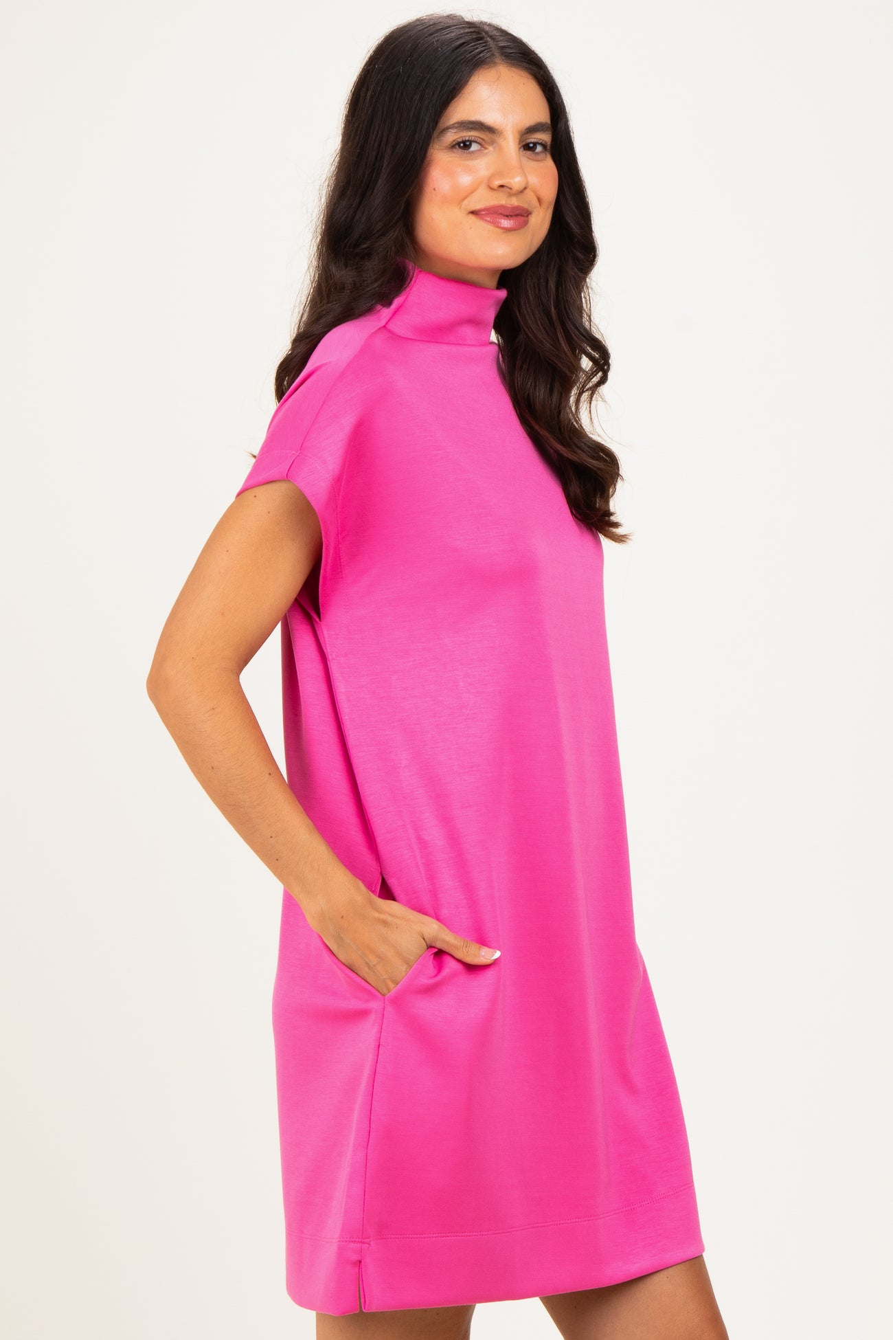 woman wearing a bright pink short sleeve dress with a mock neck and side pockets