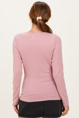 woman wearing a light pink long sleeve top with a fitted style, shown from the back
