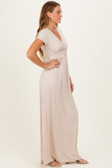 woman wearing a light beige short sleeve maxi dress with a knot detail at the waist