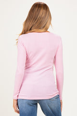 woman wearing a light pink ribbed long sleeve maternity top, seen from the back