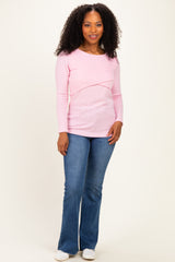 woman wearing a light pink long sleeve top with a crossover design and paired with flared blue jeans