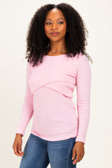 woman wearing a pink ribbed long sleeve top with a twisted front design and styled hair