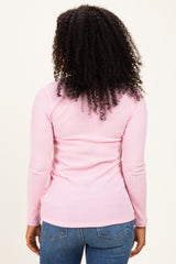 woman wearing a fitted light pink ribbed long sleeve top with a round neckline and back detail, styled with blue jeans
