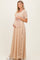 woman wearing a beige lace maternity gown with short sleeves, gently holding her baby bump