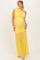 woman wearing a yellow one-shoulder maternity dress with ruched detailing and a flowing skirt, showcasing her baby bump