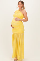 woman wearing a yellow one-shoulder maxi maternity dress with ruched details and a visible baby bump