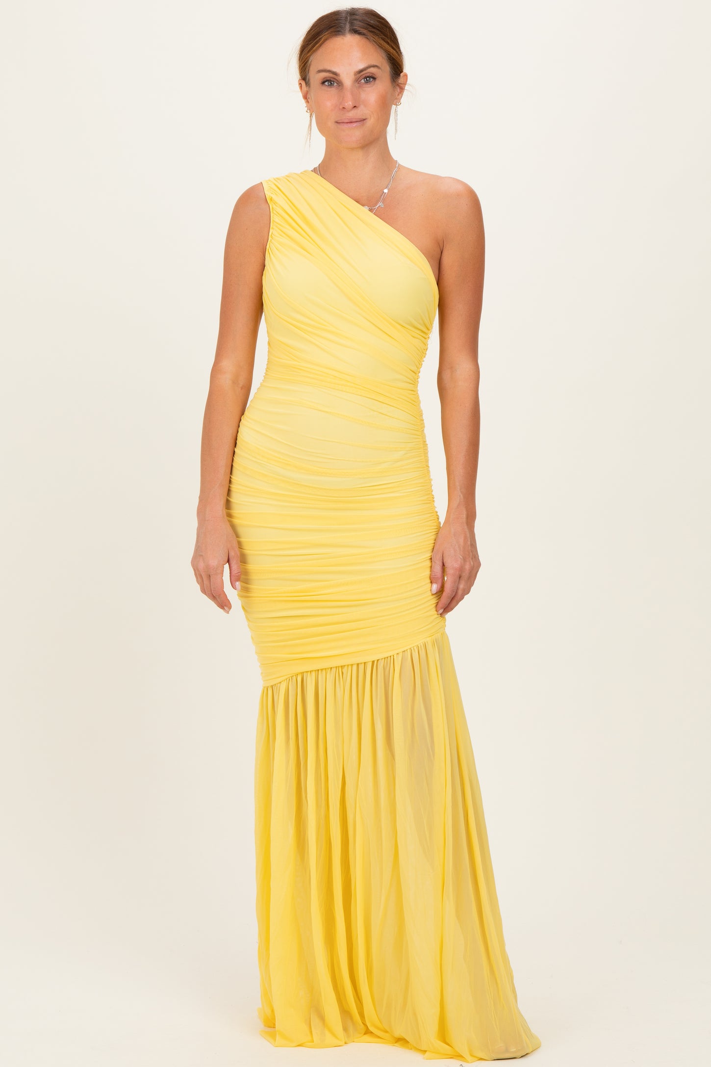 woman wearing a yellow one-shoulder ruched formal dress with a flowing skirt