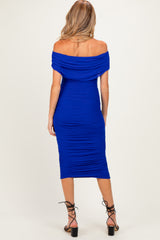 woman wearing a royal blue off-the-shoulder ruched maternity dress with a fitted silhouette and mid-calf length