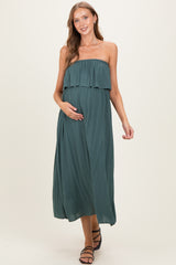 woman wearing a dark teal strapless maternity maxi dress with a ruffled top and holding her baby bump