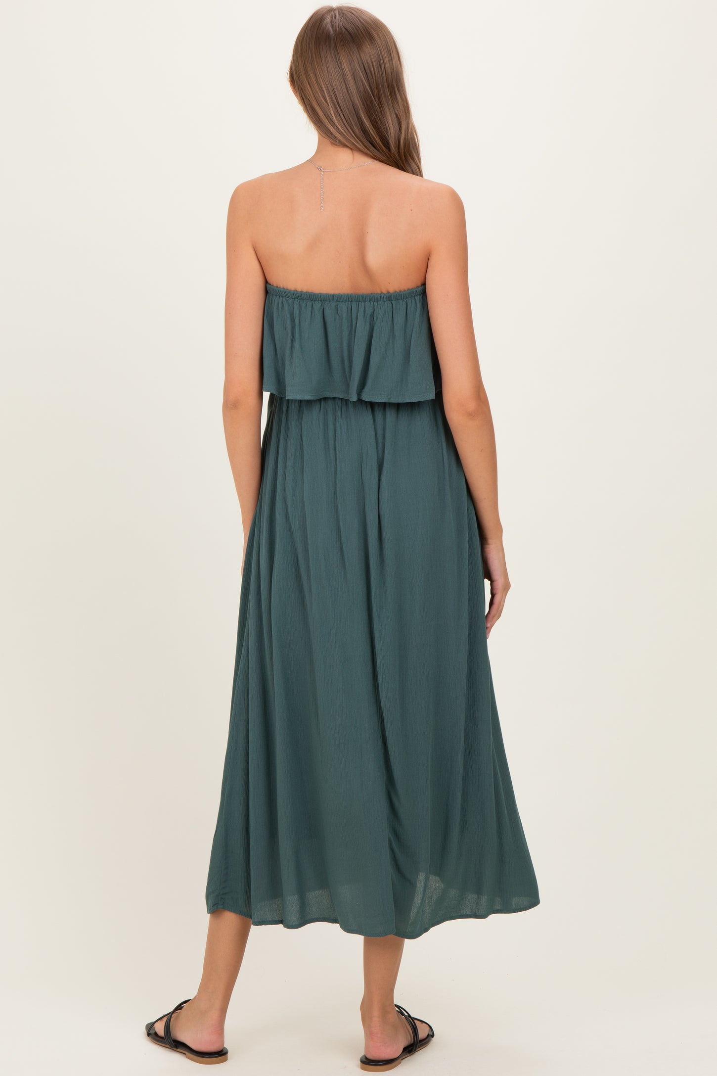 woman wearing a green strapless maternity maxi dress, showing a flowy silhouette and back view