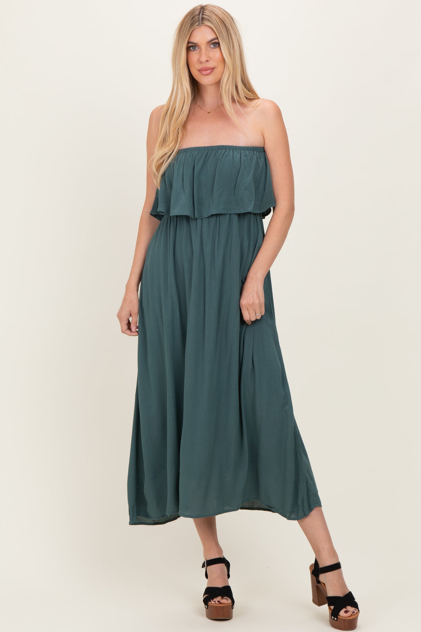 woman wearing a teal strapless maxi dress with a ruffled layer and flowing silhouette